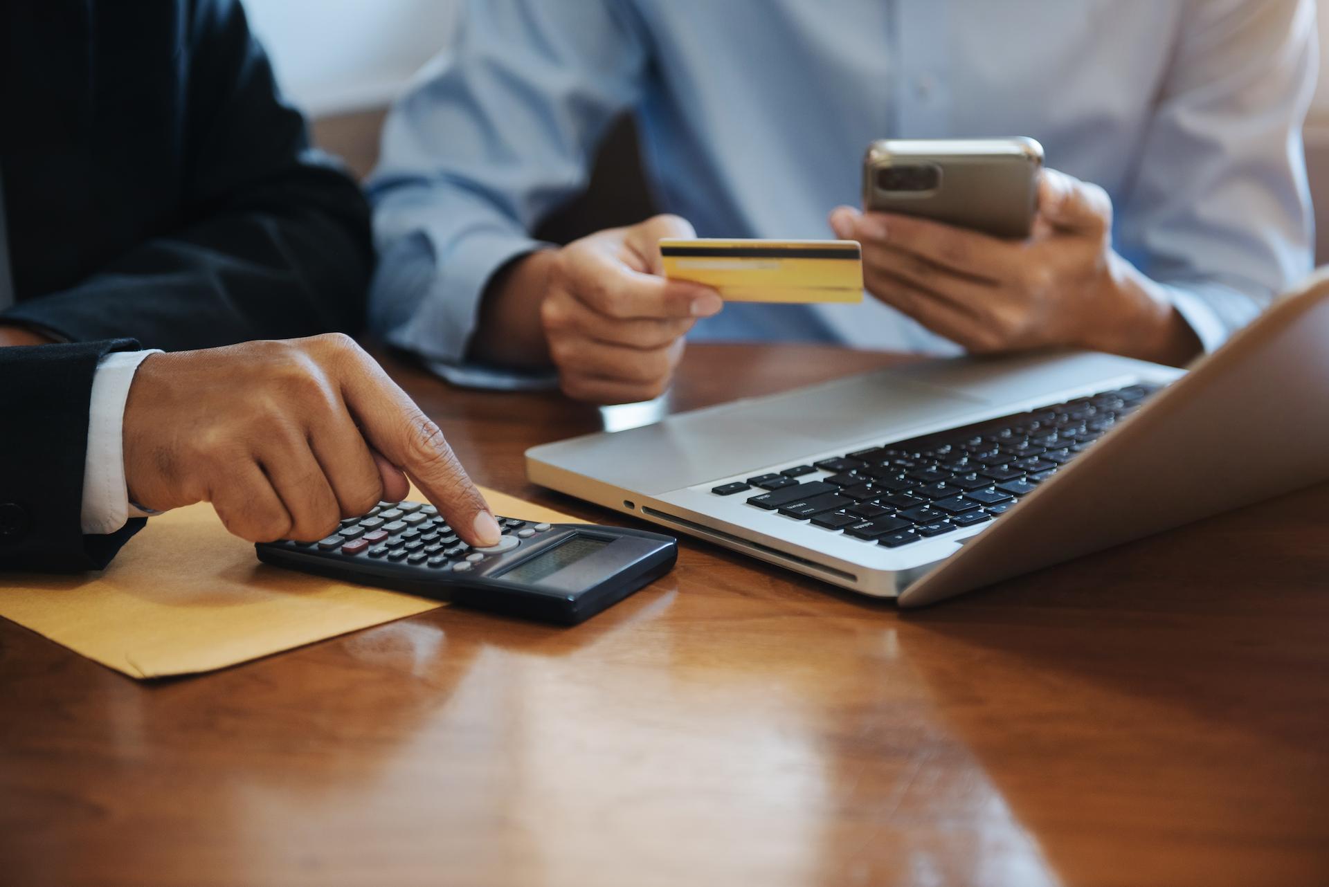 Accountants in a small business working using a calculator and macbook using accounting software