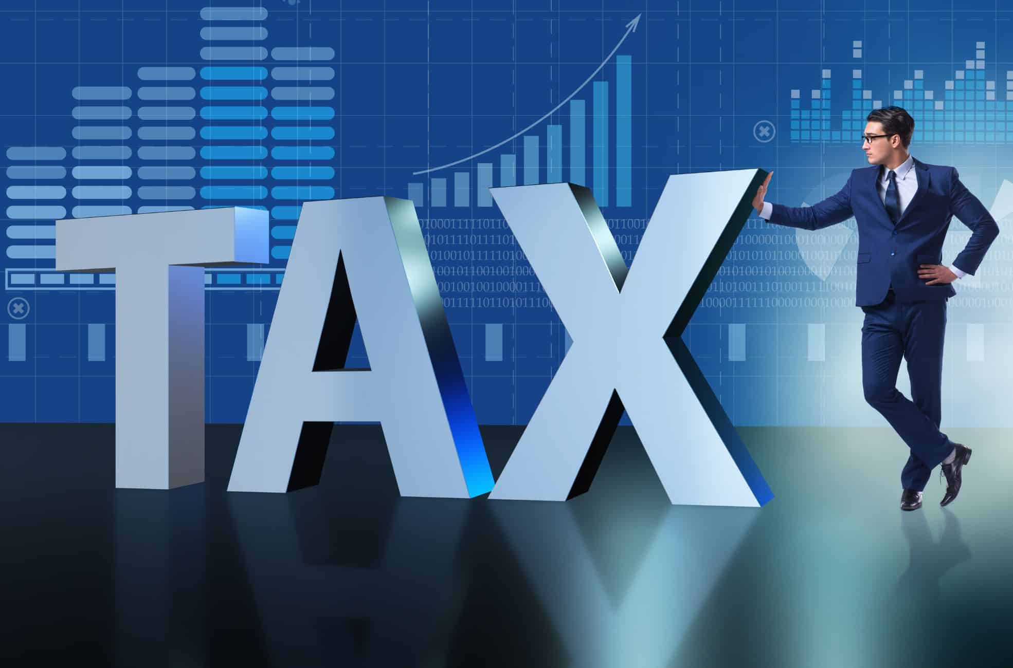 Businessman Standing Next To Giant Letters Spelling "Tax"