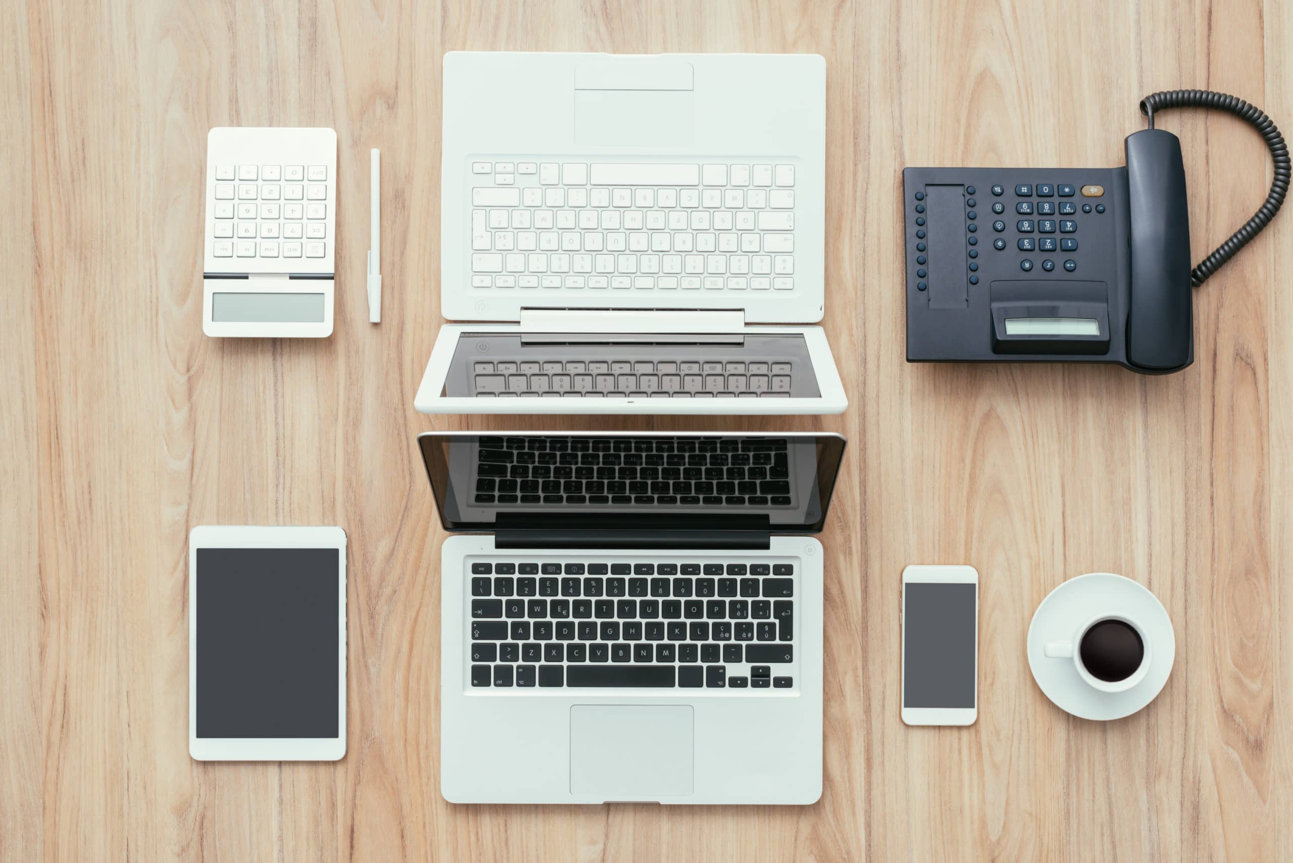 Flexidesk business center desk with laptops, smartphones, tablet, telephone, and calculator in the UAE.