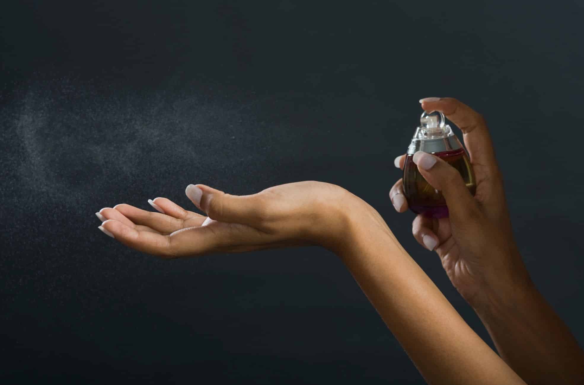 Man's Hand Spraying Perfume On Woman's Wrist